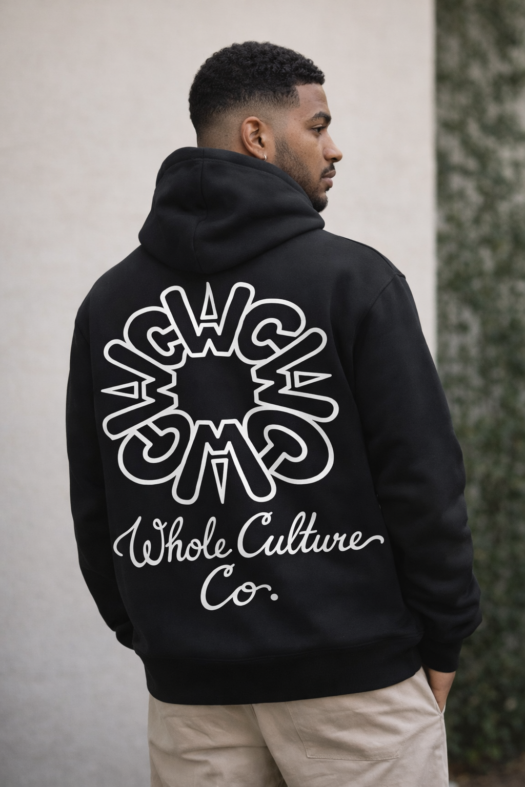 Model wearing the WCWC Circle Logo Hoodie in black, outdoor studio setting